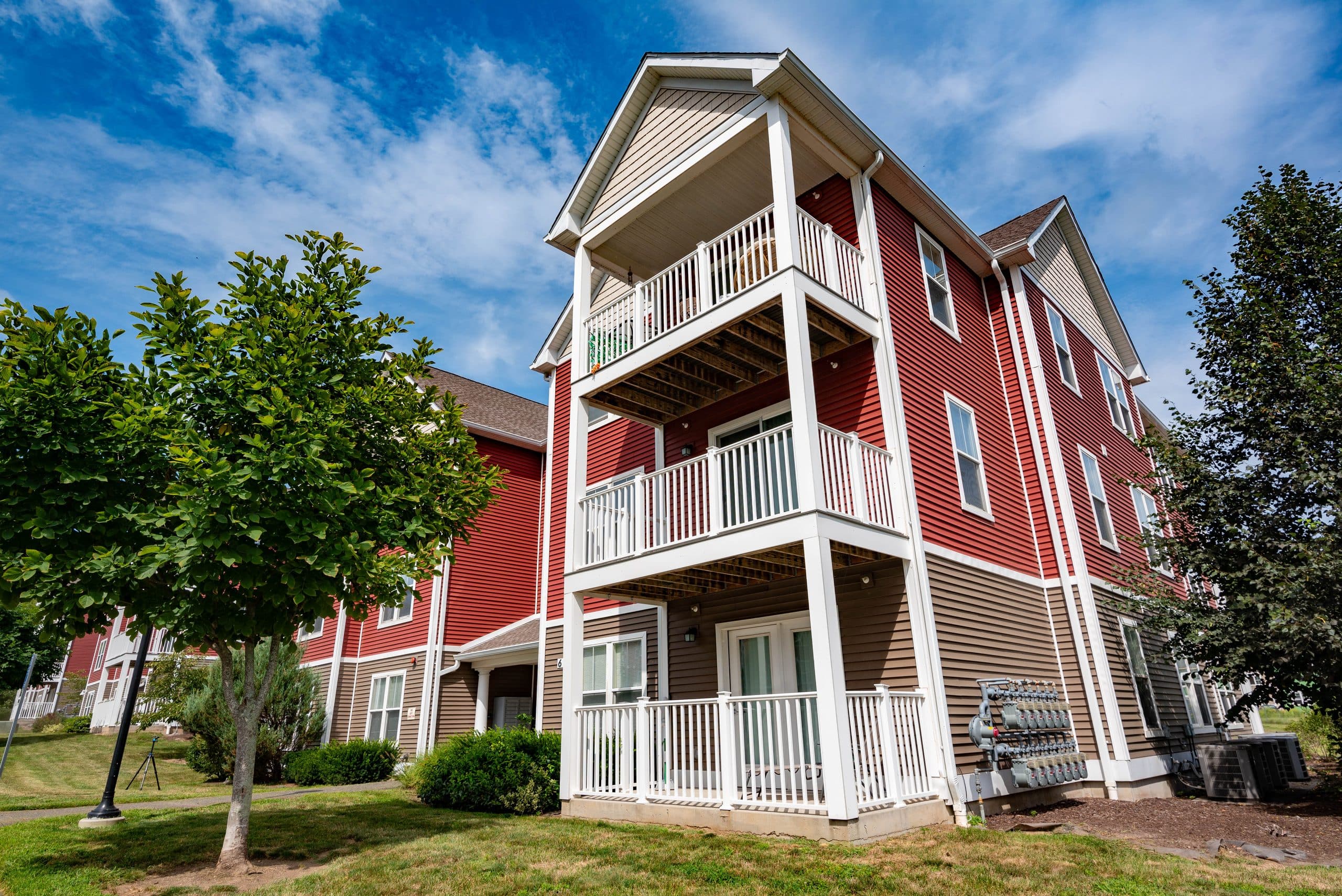 Corner of a Brook Hill Village building showing three storeys of private balconies against a blue sky