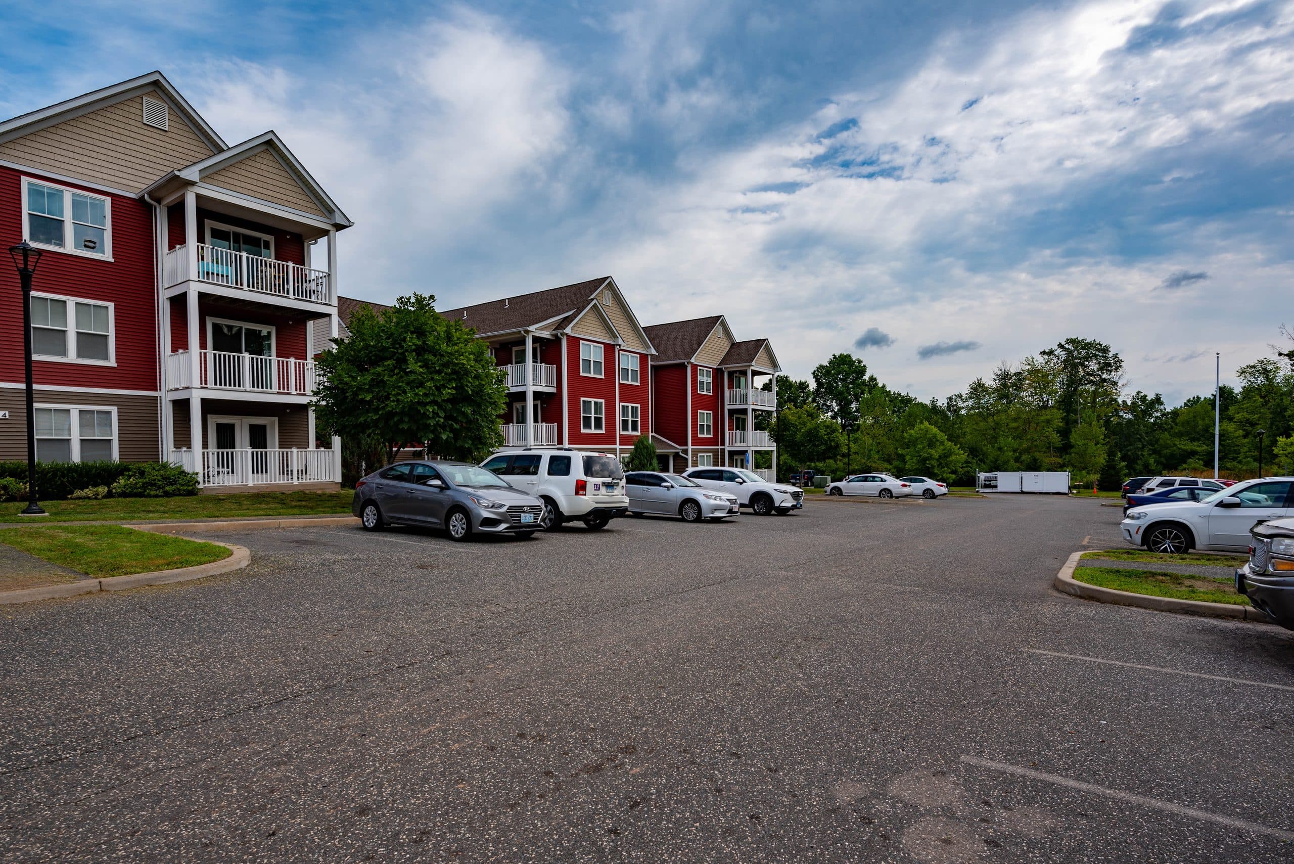 Off-street resident parking at Brook Hill Village with the apartment buildings and open lawn behind